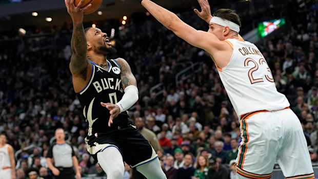 Dec 19, 2023; Milwaukee, Wisconsin, USA; Milwaukee Bucks guard Damian Lillard (0) shoots around San Antonio Spurs center Zach Collins (23) during the first quarter at Fiserv Forum.